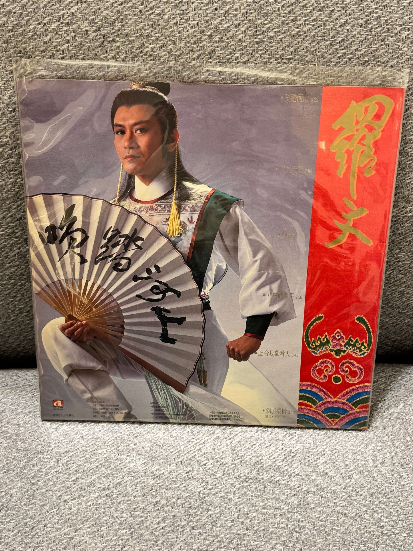 羅文 – Roman專輯封面,展示主唱手持扇子,搭配色彩鮮豔的設計和表情。