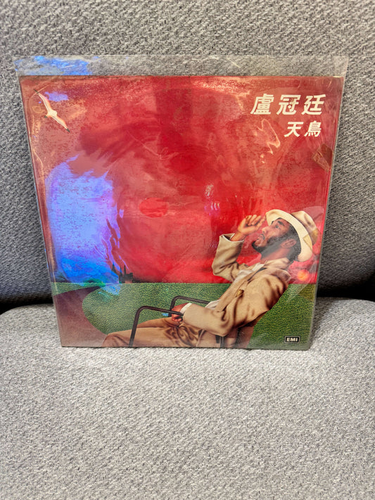盧冠廷 – 天鳥 Album Cover featuring a man in a hat, enjoying the view with a vibrant red background.