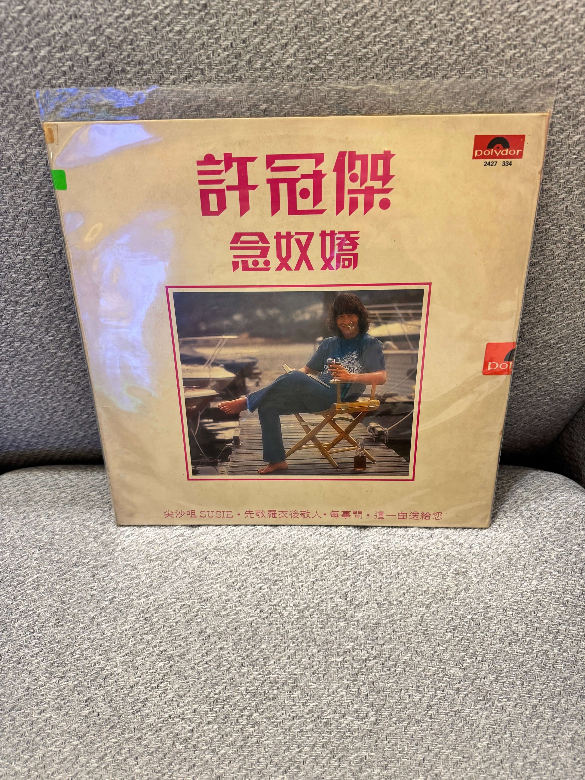 許冠傑 – 念奴嬌 album cover featuring the artist sitting in a chair outdoors.